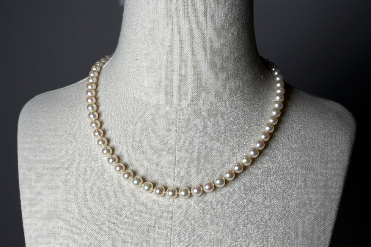 Pearl necklace on a mannequin against a dark background