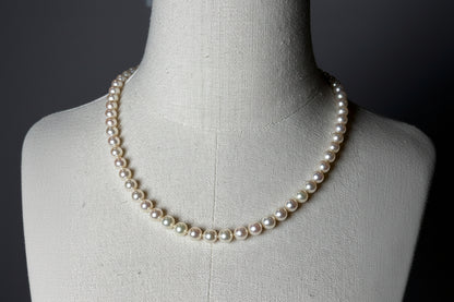 Pearl necklace on a mannequin against a dark background