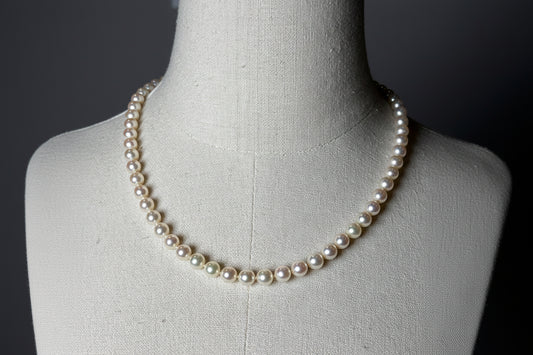 Pearl necklace on a mannequin against a dark background