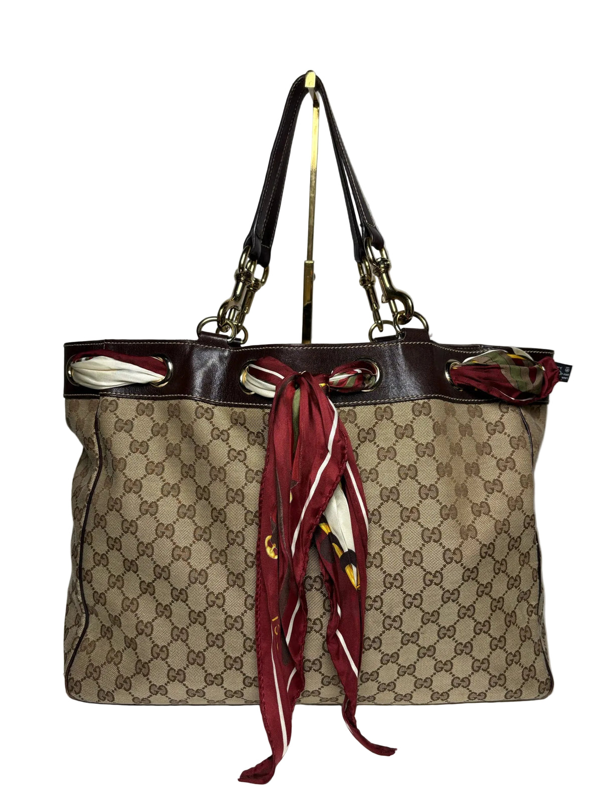 Brown Gucci bag with a red printed scarf around the trim