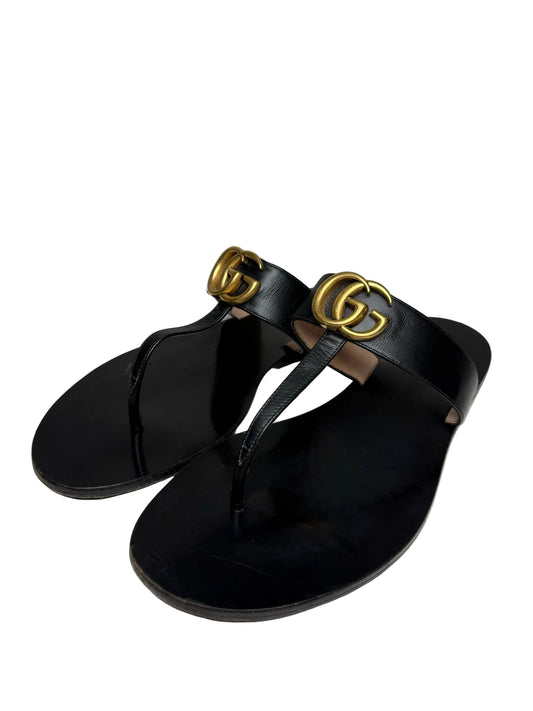 Black Gucci flip-flop sandals with the classic gold Gucci "GG" logo.