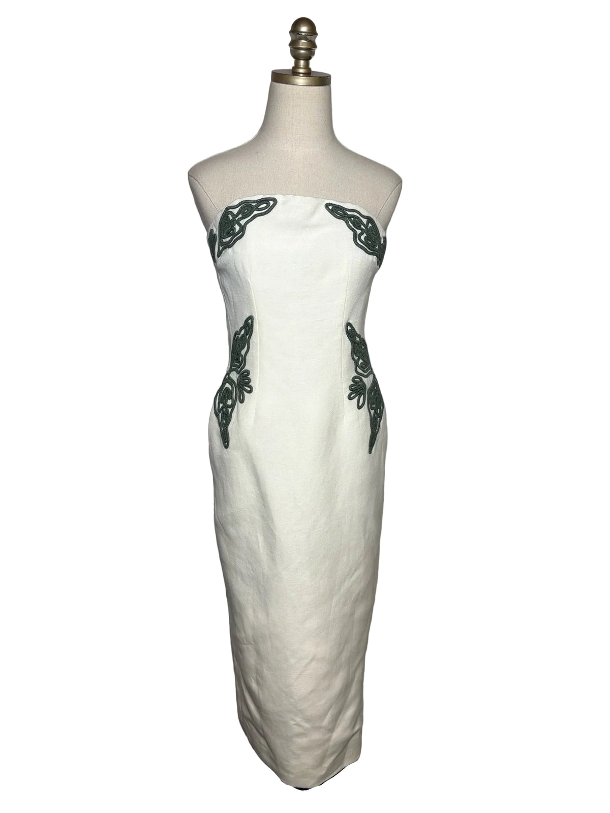 White strapless dress with green embroidery on a mannequin.
