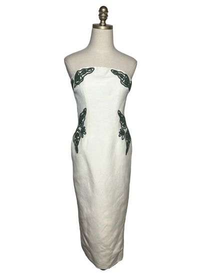 White strapless dress with green embroidery on a mannequin.