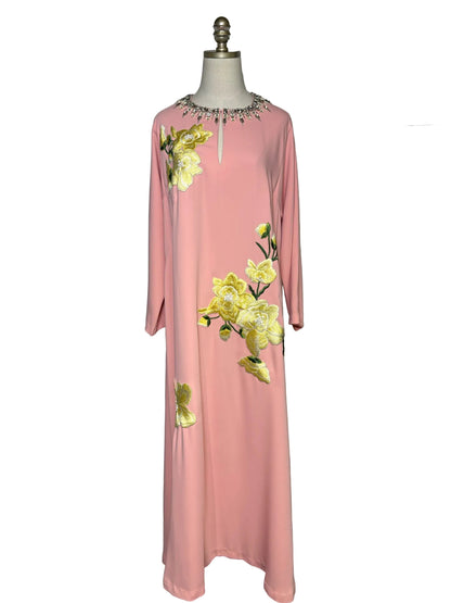 Long light pink dress with long sleeves and yellow floral embroidery.  The dress has a crystal embellished neckline and is on a mannequin in front of a white background.