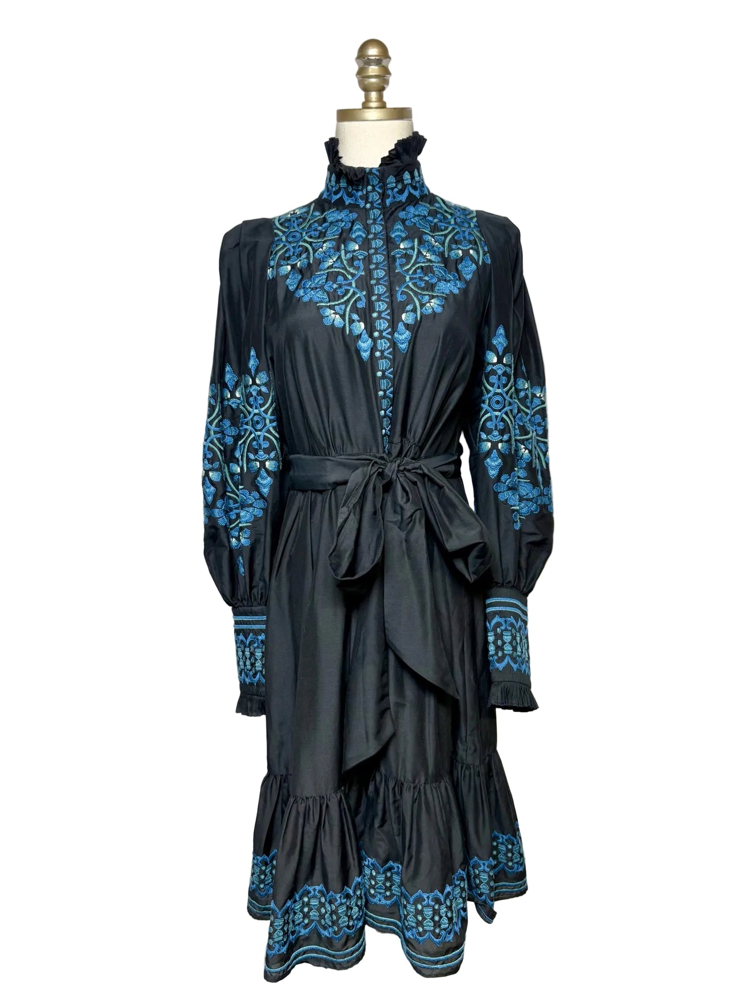 Black dress with blue embroidery on a mannequin in front of a white background 