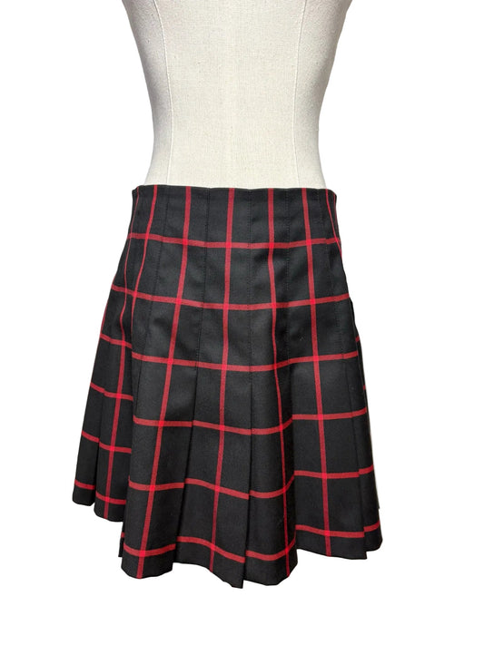 Black pleated skirt with red vertical and horizontal stripes on a mannequin.